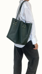 Person wearing a white shirt and dark green tote bag on a plain background