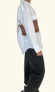 Person wearing a white shirt with brown accents and black pants on a white background