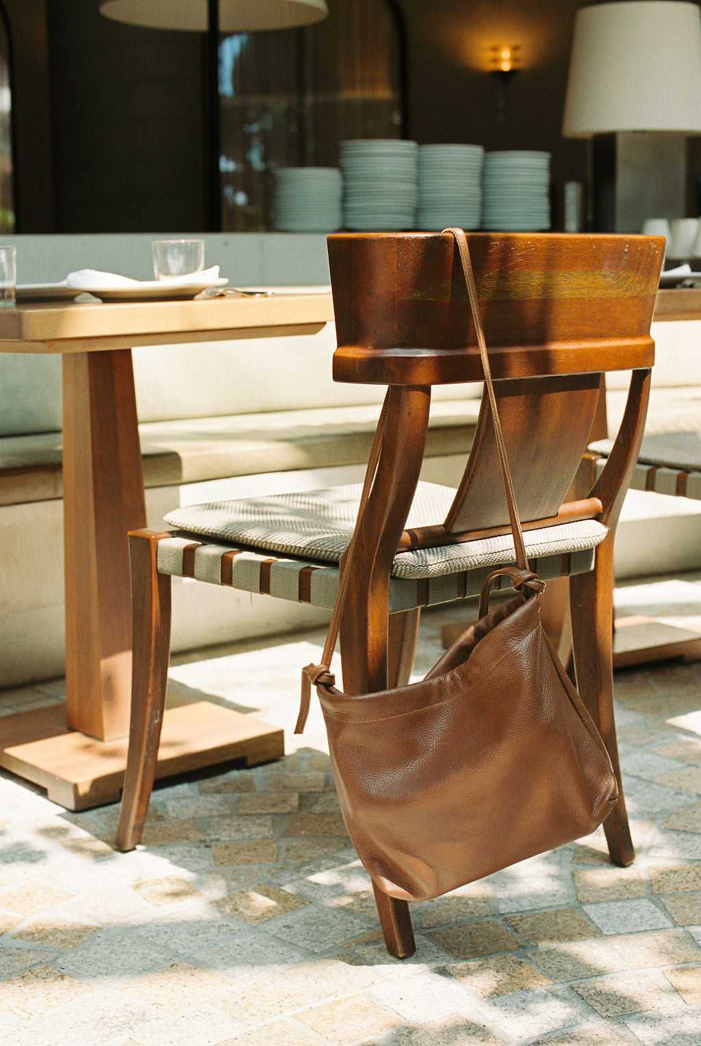 Brown leather handbag on a wooden chair in a dining area