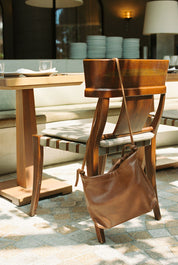 Brown leather handbag on a wooden chair in a dining area