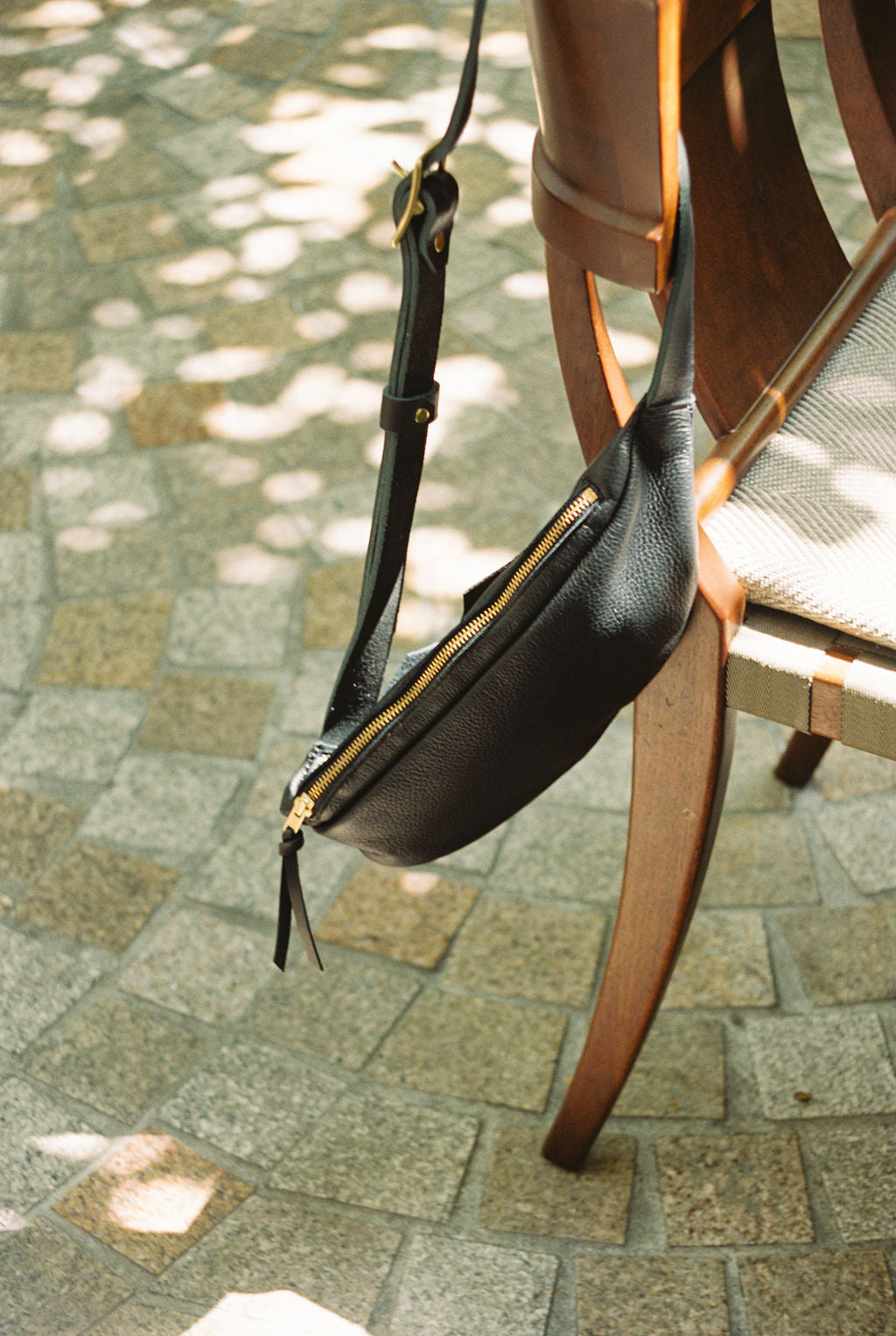 Black leather bag with gold zipper on a chair outdoors