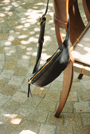 Black leather bag with gold zipper on a chair outdoors