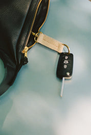 Car key with remote on a black leather bag against a light blue background