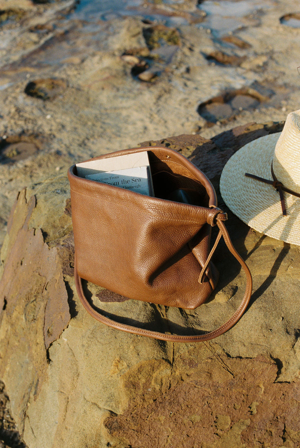 Brown leather bag with a hat on a stone surface