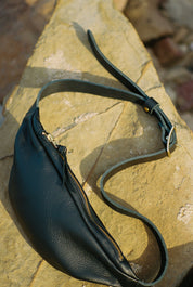 Black leather bag with a strap on a stone surface