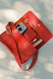 Red handbag with a camera and lipsticks on a light background