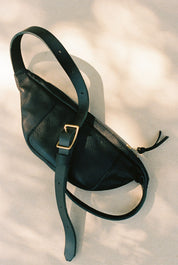 Black leather Bag with a gold buckle on a light background