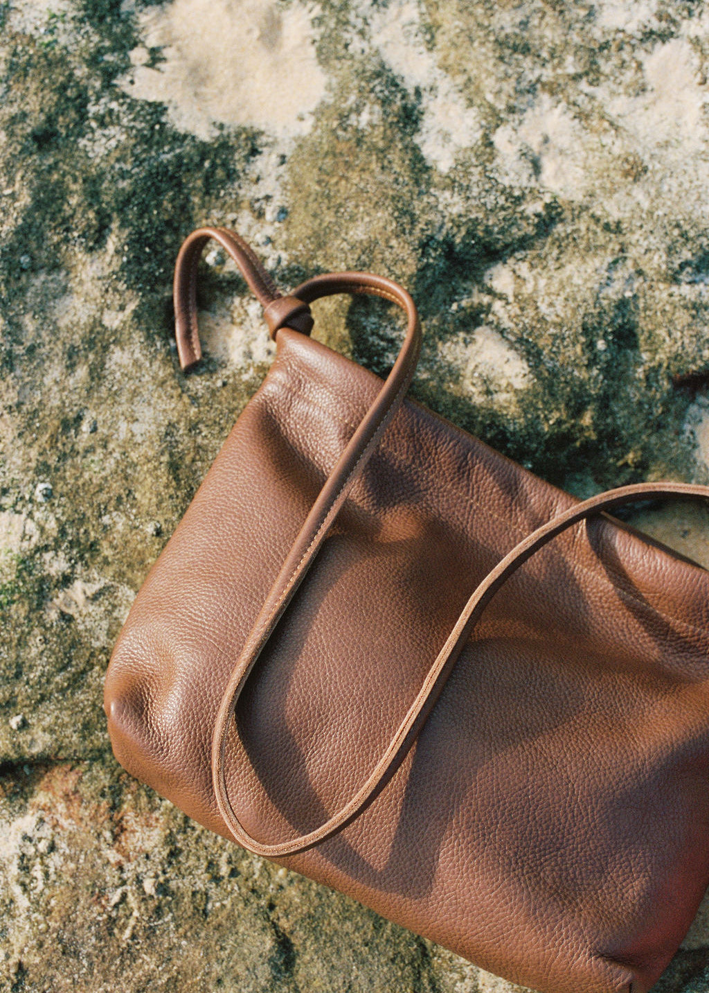 Brown leather handbag on a textured stone surface