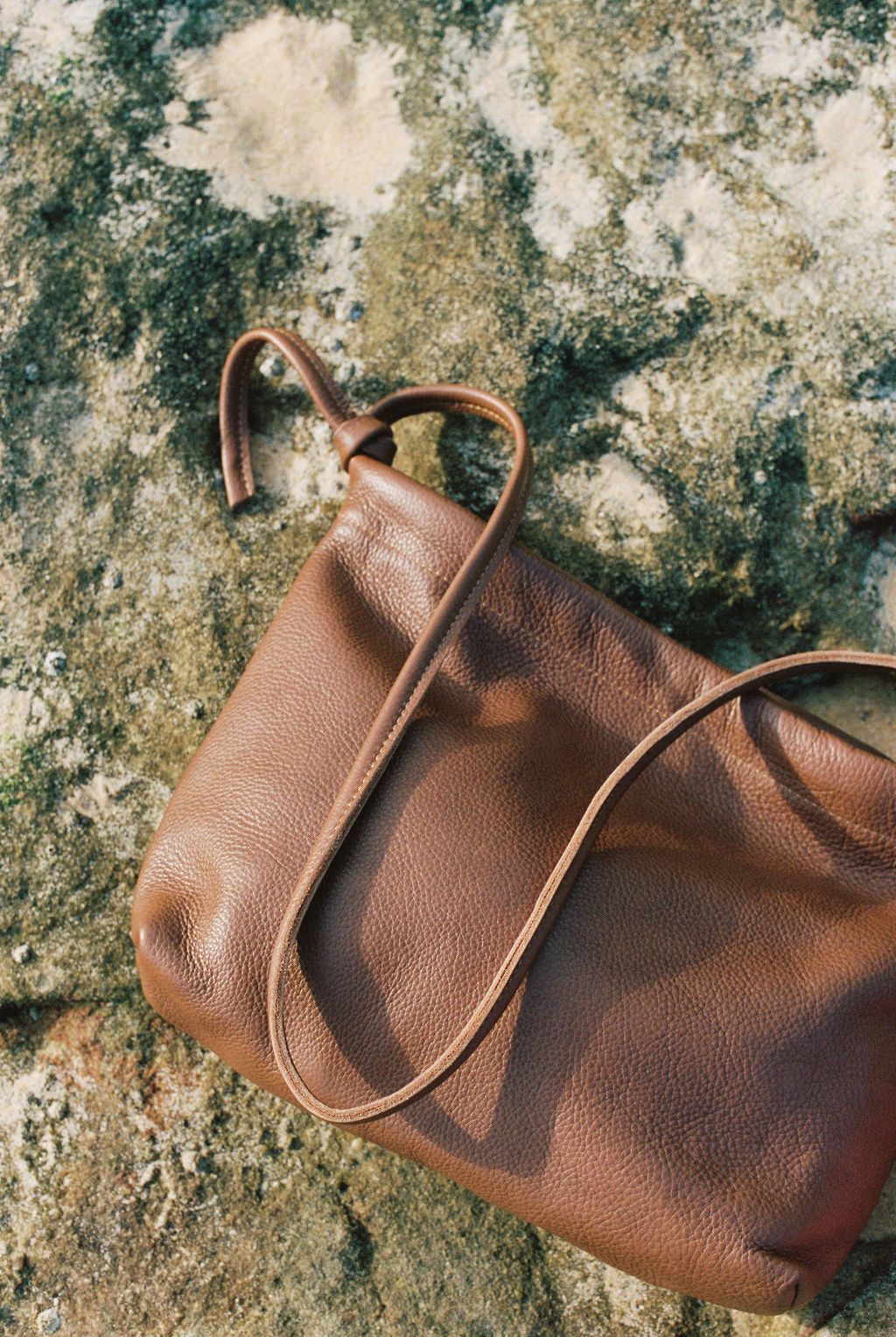 Brown leather handbag on a textured stone surface