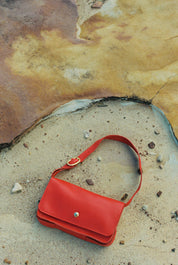 Red handbag on a textured surface with pebbles