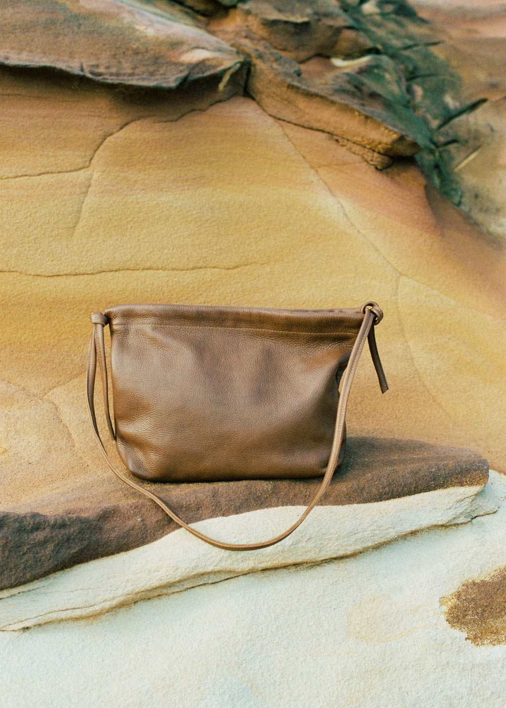 Brown leather handbag on a rock with natural background