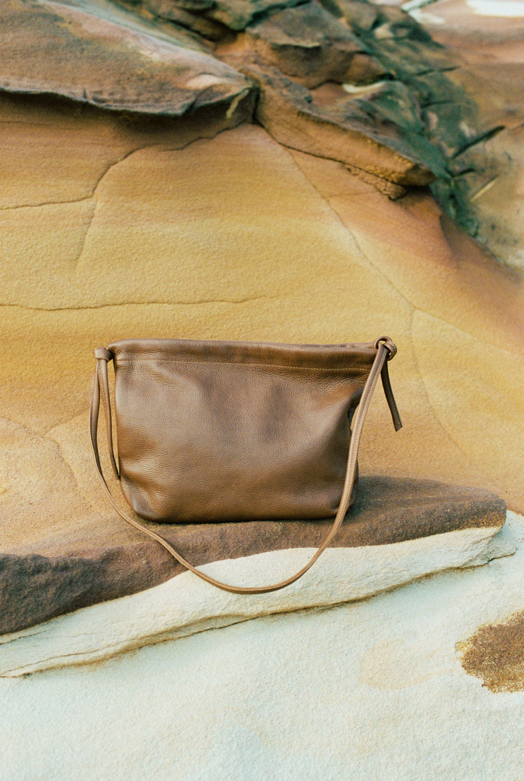 Brown leather handbag on a rock with natural background