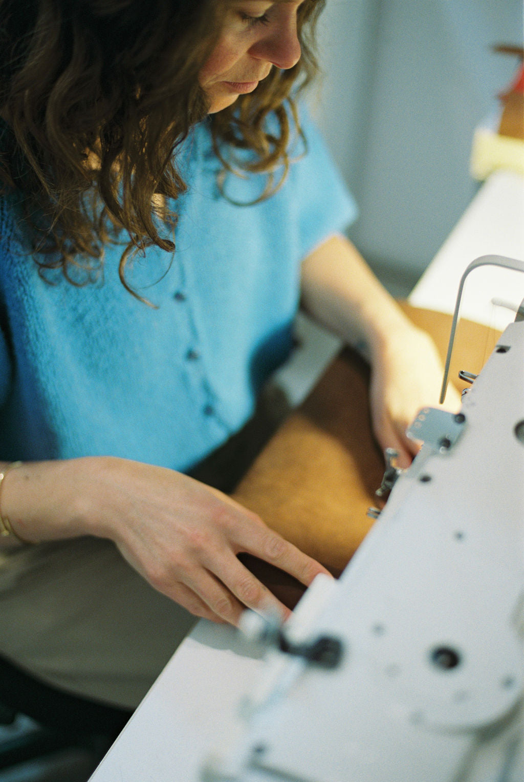 Person operating a sewing machine with focus on hands and machine.